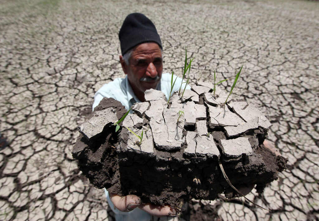 An Egyptian farmer holds a handful of soil to show the dryness of the land due to drought in a farm formerly irrigated by the river Nile, in Al-Dakahlya